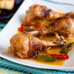 Chicken drumsticks with peppers and paprika on a white platter