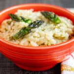 An orange bowl full of asparagus risotto with a napkin