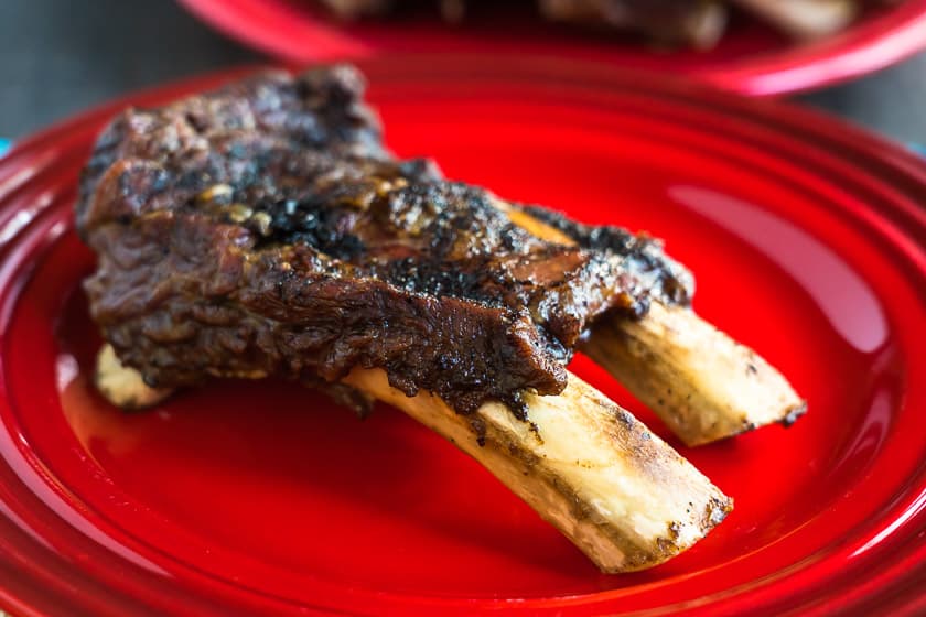 A two-bone slab of beef back ribs on a red plate