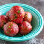 A bowl of cooked baby red potatoes sprinkled with parsley