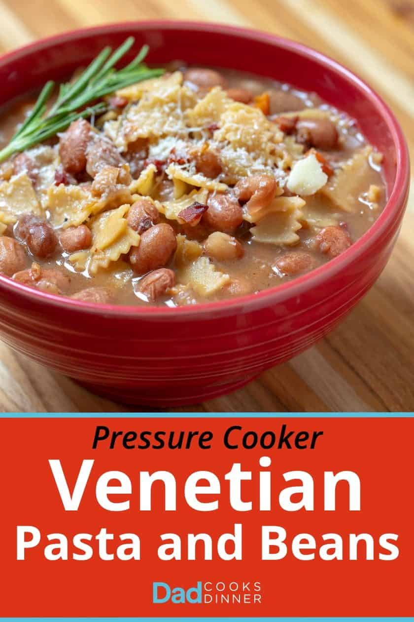 A red bowl full of pressure cooker Venetian pasta and beans, brown beans and pasta garnished with a sprig of rosemary and a sprinkling of grated white cheese