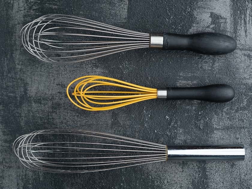 A balloon whisk, a mini-whisk, and a french whisk on a black background