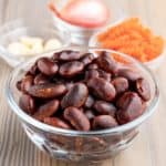 A bowl of cooked scarlet runner beans on a white table