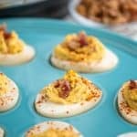 A turquoise plate of deviled eggs with bacon