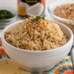 A bowl of brown coconut rice, sprinkled with toasted coconut flakes and a little minced cilantro