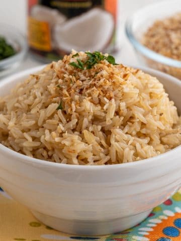 A bowl of brown coconut rice, sprinkled with toasted coconut flakes and a little minced cilantro
