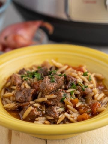 A yellow bowl of youvetsi - greek lamb stew with orzo