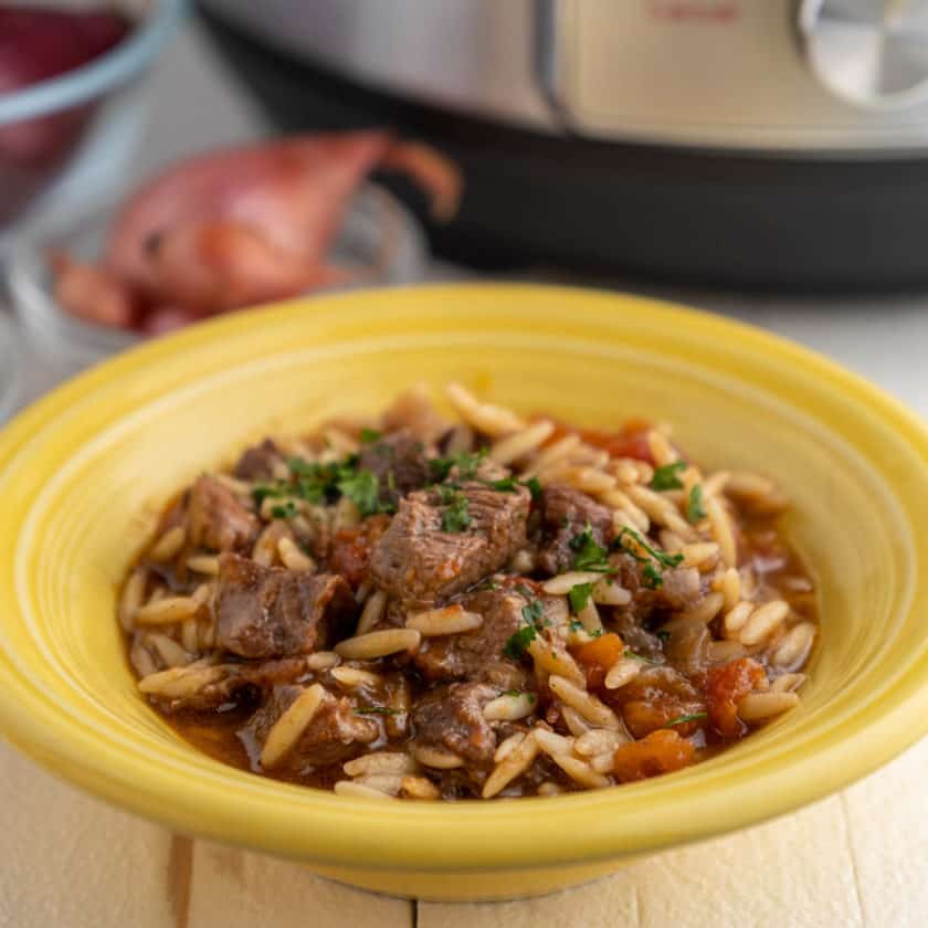 A yellow bowl of youvetsi - greek lamb stew with orzo