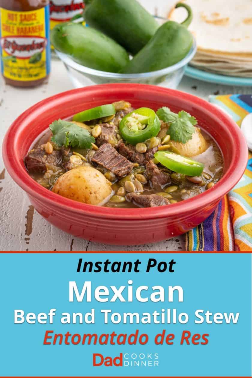 A red bowl of beef and tomatillo stew, with potatoes, sprinkled with sliced jalapeno, cilantro, and pepitas, with tortillas, jalapenos, and hot sauce in the background