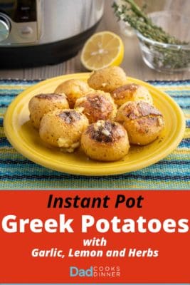 A plate of cooked potatoes, sprinkled with garlic and herbs, on a blue and yellow napkin with a pressure cooker, herbs, and a lemon in the background