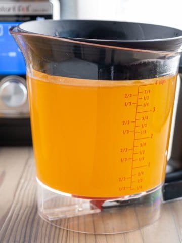 A fat separator full of rotisserie chicken broth, with an instant pot in the background