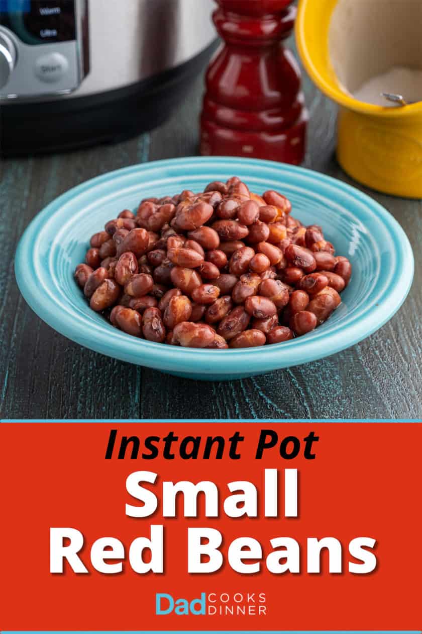 A bowl of red beans in front of a pressure cooker, a salt pig, and a pepper grinder