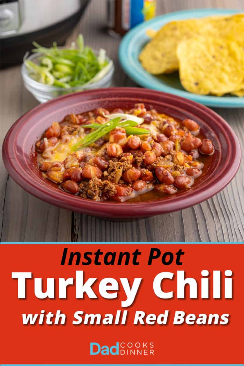 A bowl of turkey and small red bean chili, with minced green onions, tortilla chips, and an Instant Pot in the background.