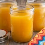 Canning jars full of bone broth with a napkin and a canning jar lid in the foreground