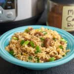 A bowl of Cajun dirty rice with an instant pot and a jar of Cajun seasoning in the background