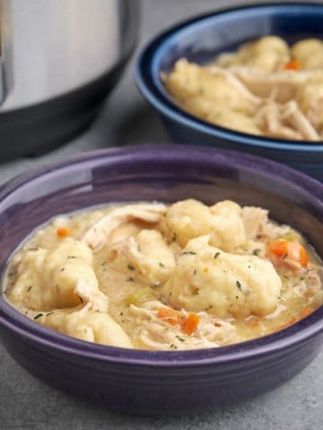 Two bowls of chicken and dumplings, with an Instant Pot in the background, on a gray table