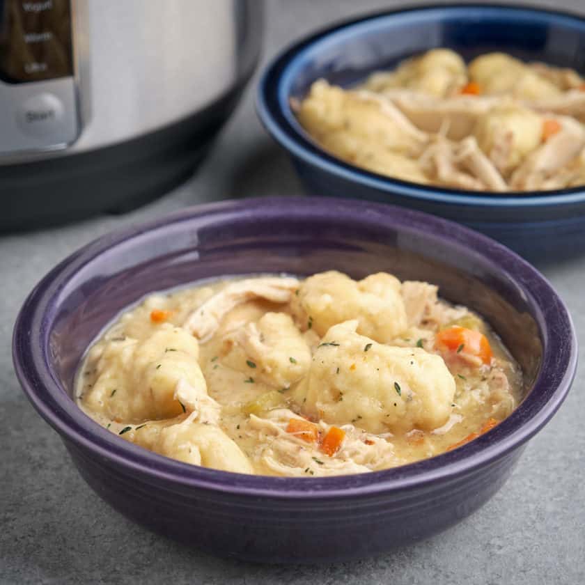 Two bowls of chicken and dumplings, with an Instant Pot in the background, on a gray table