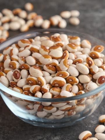 A bowl of uncooked yellow eye beans on a slate table