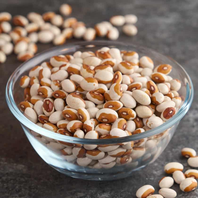 A bowl of uncooked yellow eye beans on a slate table