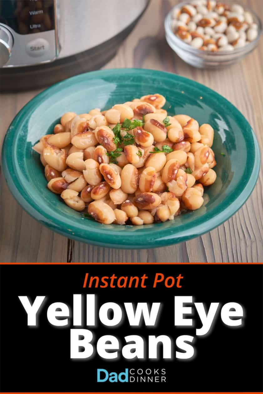 A bowl of cooked yellow eye beans on a wood table with an Instant Pot and some uncooked beans in the background