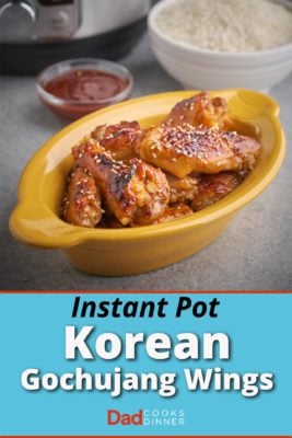 Gochujang glazed chicken wings sprinkled with sesame seeds in a yellow dish, with a bowl of gochujang, a bowl of rice, and an Instant Pot in the background.