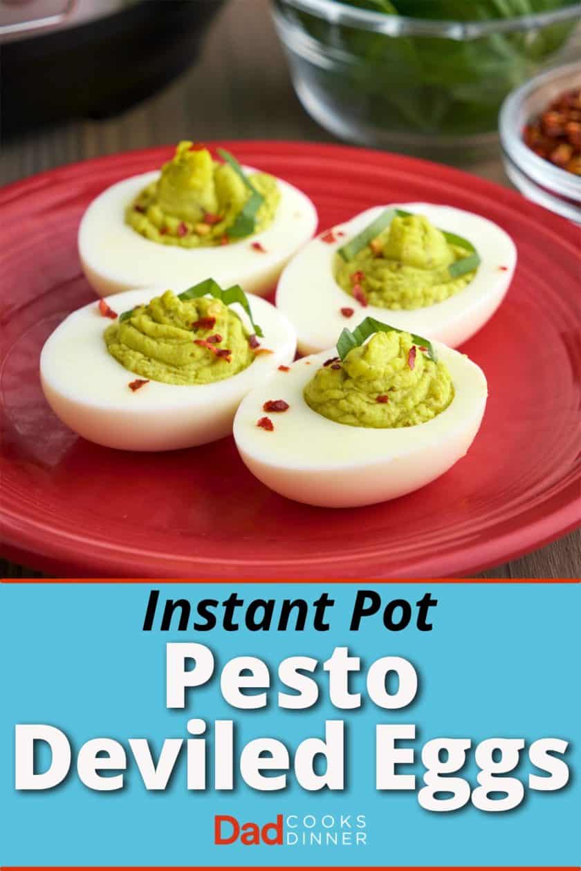 Four pesto deviled eggs, with green filling, sprinkled with basil and red pepper flakes, on a maroon plate