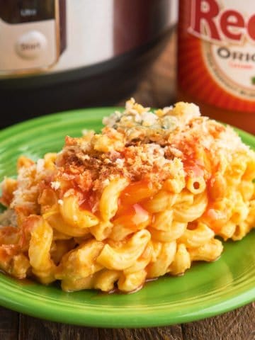 A plate of buffalo chicken mac and cheese in front of an Instant Pot and a bottle of Franks RedHot