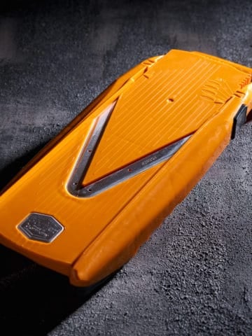 Orange mandoline on a black surface with dramatic lighting