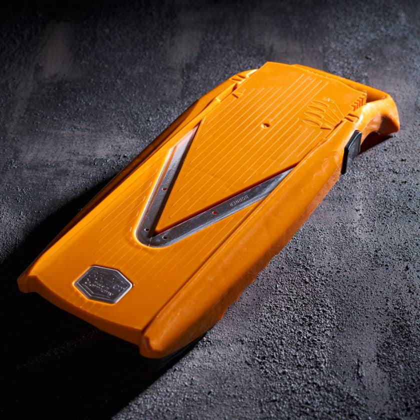 Orange mandoline on a black surface with dramatic lighting