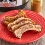 Baby back ribs with dry rub on a red plate, with an Instant Pot and a jar of dry rub in the background