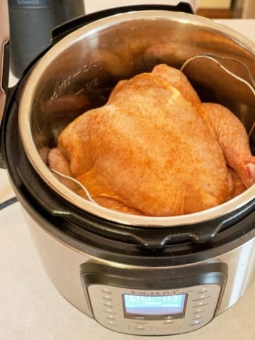 A whole chicken sprinkled with Cajun Spice Rub in an Instant Pot, ready to cook