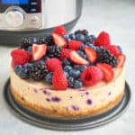 A berry cheesecake in front of an Instant Pot