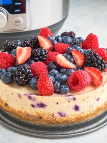 A berry cheesecake in front of an Instant Pot