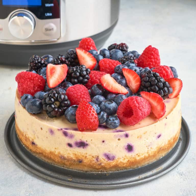 A berry cheesecake in front of an Instant Pot