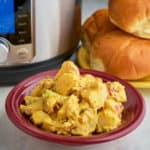 A bowl of mustard potato salad in front of a plate of hamburger buns and an Instant Pot