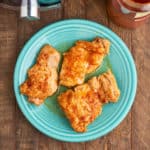 A plate of cooked chicken thighs, with an Instant Pot and a jar of paprika