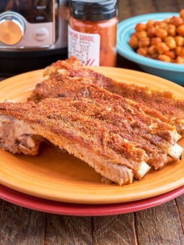 Spanish ribs on a yellow plate with smoked paprika, chickpeas, and an Instant Pot in the backgroud