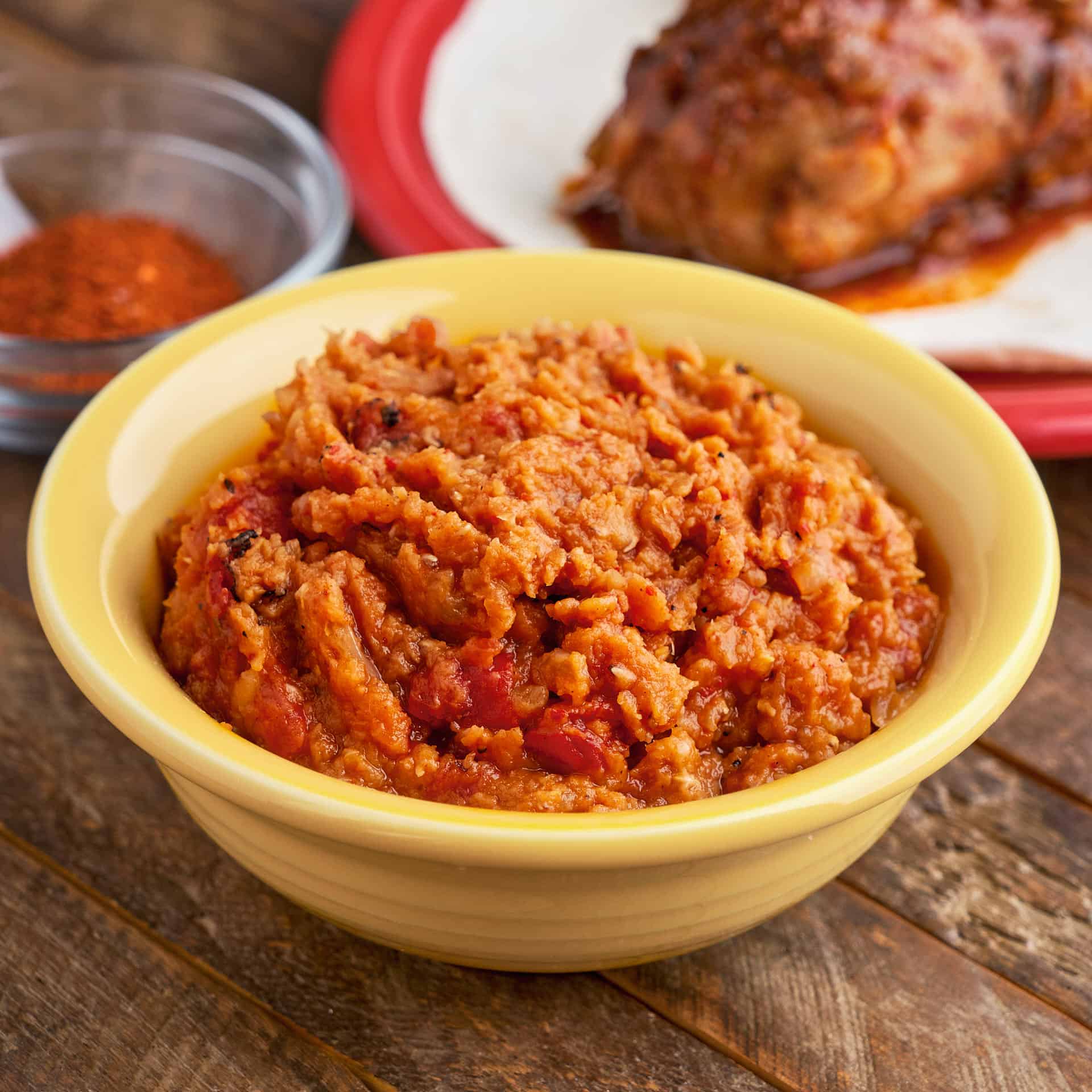 A bowl of misir wat, Ethiopian red lentils, in a yellow bowl, on a wooden table