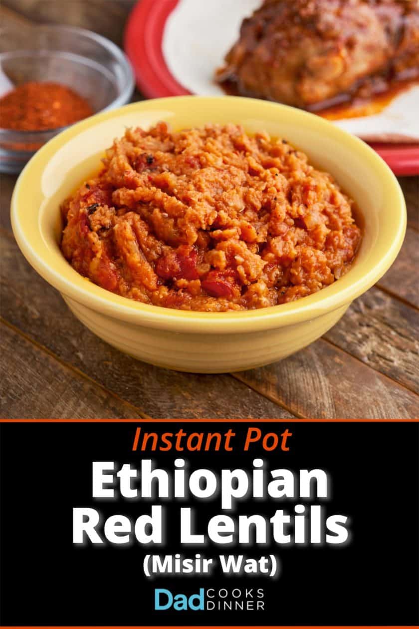 A bowl of misir wat, Ethiopian red lentils, in a yellow bowl, on a wooden table