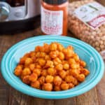 A bowl of garbanzos with Spanish smoked paprika, with a bag of garbanzos, a jar of smoked paprika, and an Instant Pot in the background