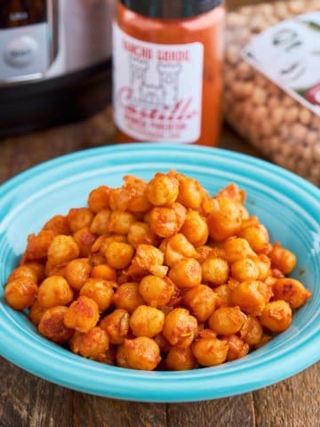 A bowl of garbanzos with Spanish smoked paprika, with a bag of garbanzos, a jar of smoked paprika, and an Instant Pot in the background