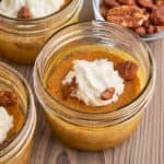 A canning jar mini pumpkin pie, with whipped cream and pecans sprinkled on top