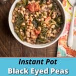 A bowl of black eyed peas and collard greens on a wood table with a bag of beans, a napkin, and a spoon