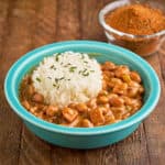 A bowl of Cajun pinto beans and rice, with a smaller bowl of spices behind them