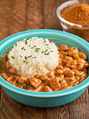 A bowl of Cajun pinto beans and rice, with a smaller bowl of spices behind them