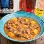 A bowl of beef stew with sweet potatoes and jalapeños, with an Instant Pot, a glass of beer, and a bottle of Top Chico in the background