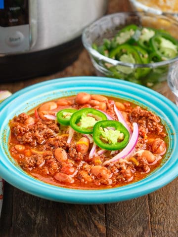 A bowl of ground buffalo chili, with an Instant Pot and sliced toppings in the background