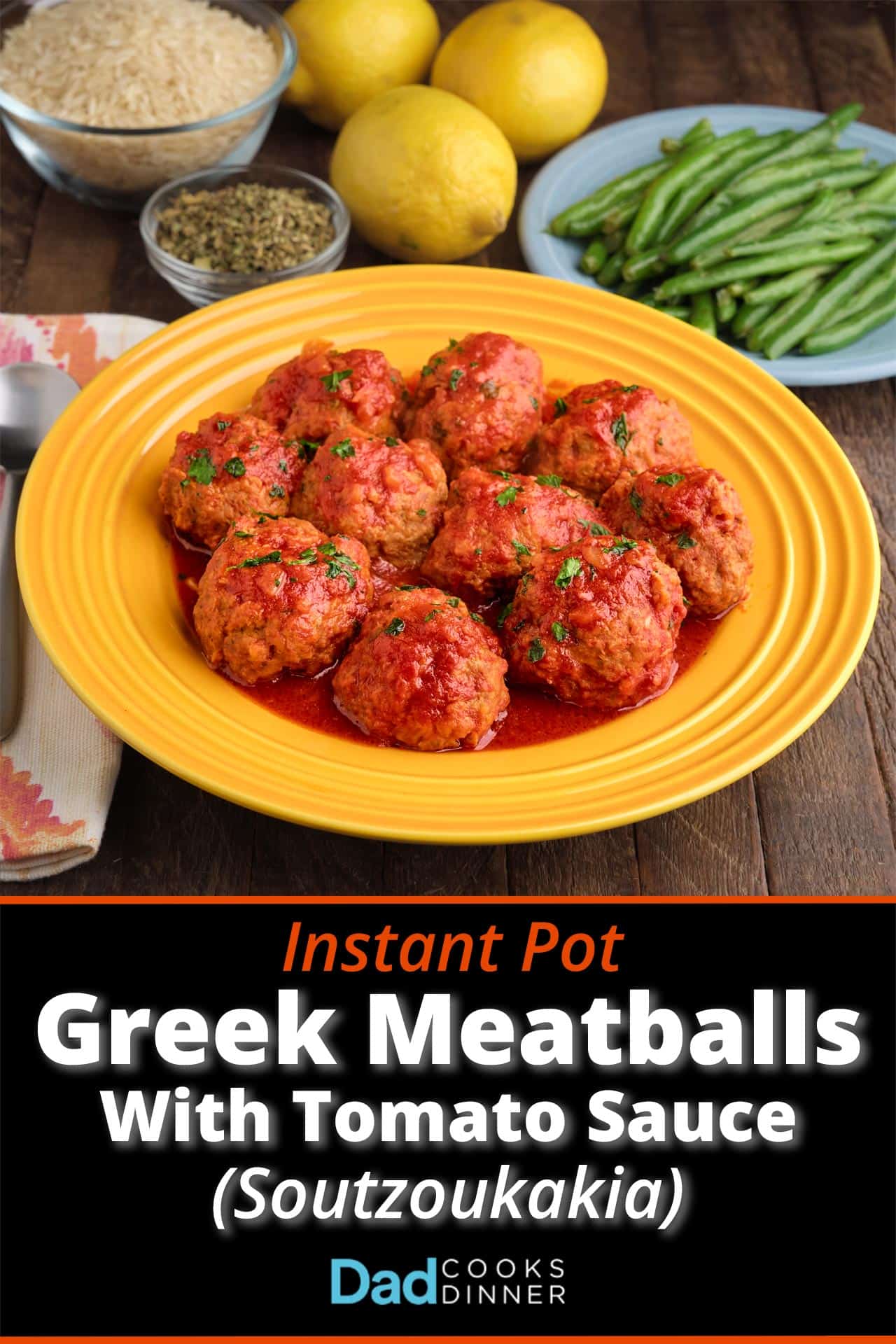 A plate of Greek meatballs in tomato sauce, with green beans, lemons, oregano, and rice in the background