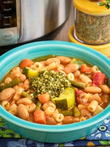 A bowl of Provencal pesto soup in front of an Instant Pot and a jar of spices