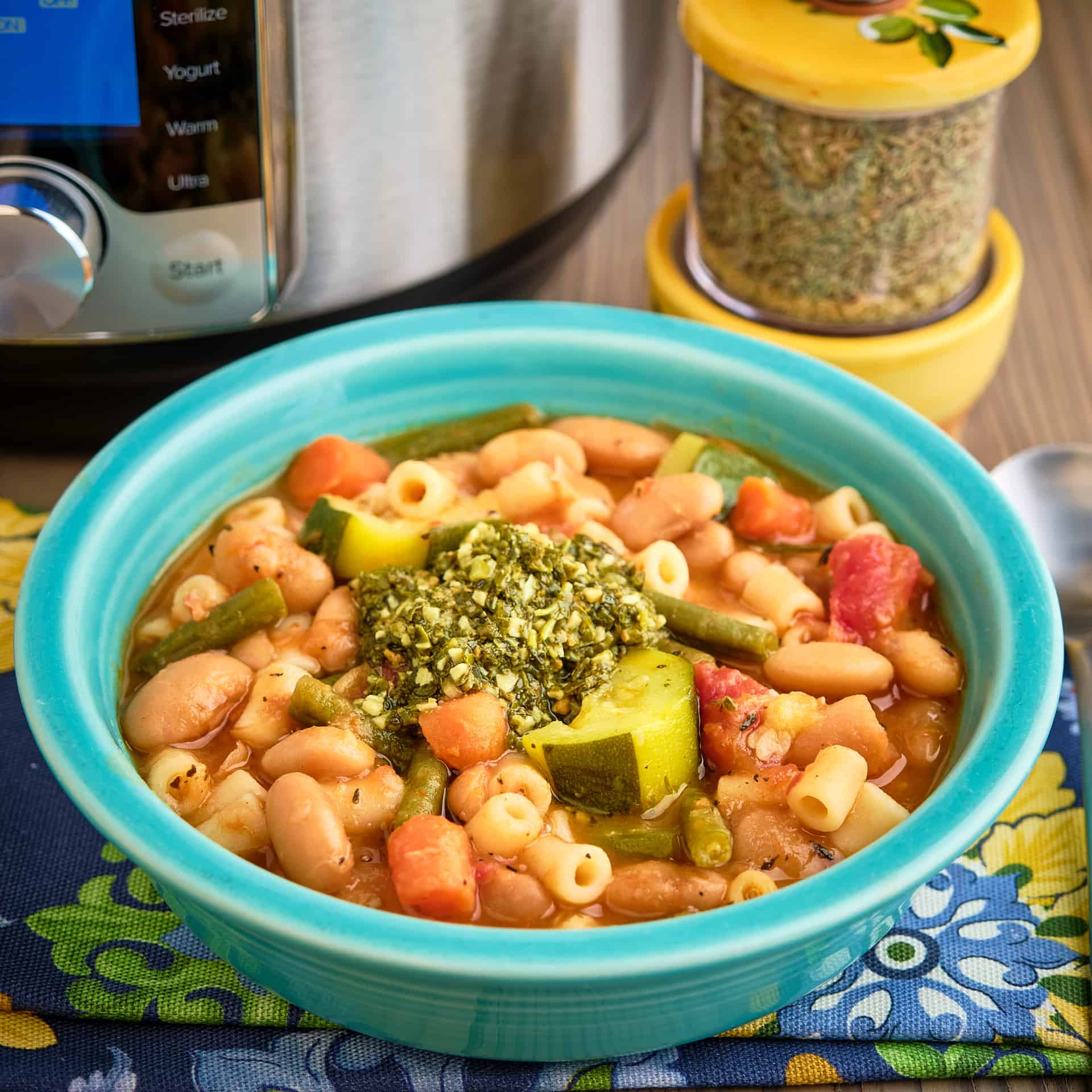 A bowl of Provencal pesto soup in front of an Instant Pot and a jar of spices